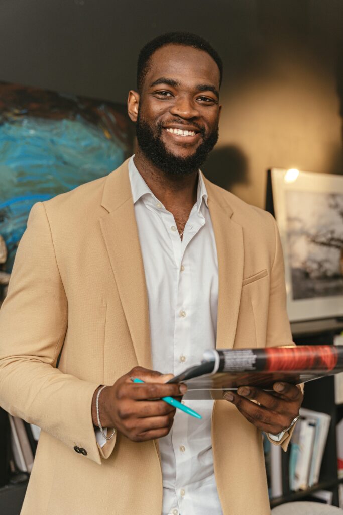 pexels-photo-8837549-8837549 Smiling black businessman holding documents in a modern office setting.